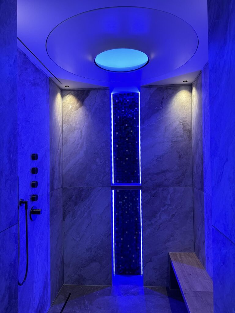 Luxe inloopdouche met blauwe LED-verlichting en natuursteen afwerking