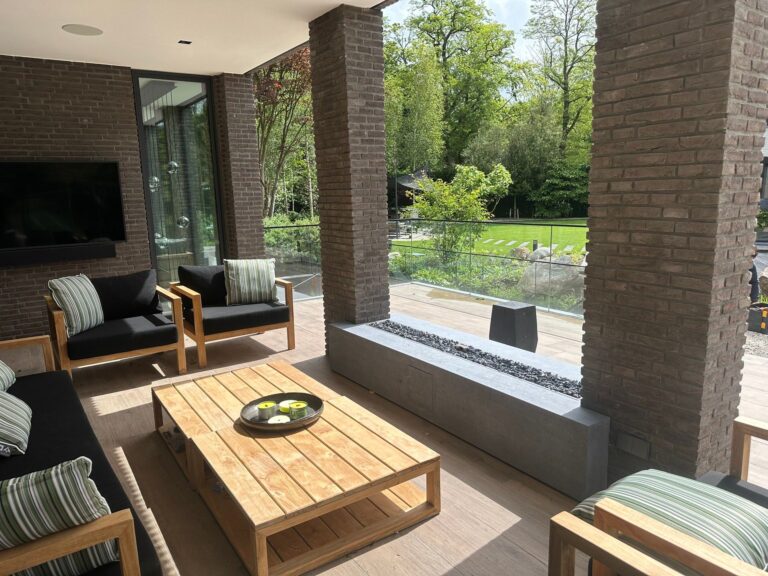 Overdekt terras met moderne zithoek en zicht op de tuin