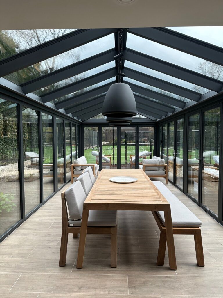 Glazen serre met eettafel en zicht op de tuin
