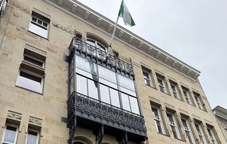 Historische gevel van een rijksmonument met sierlijk zwart balkon en glazen pui