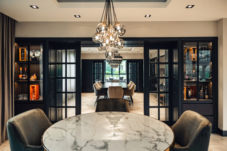 Luxe eetkamer met donkere maatwerkkasten en kroonluchter