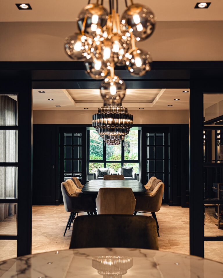 Entree naar luxe eetkamer met kroonluchter en maatwerkkasten