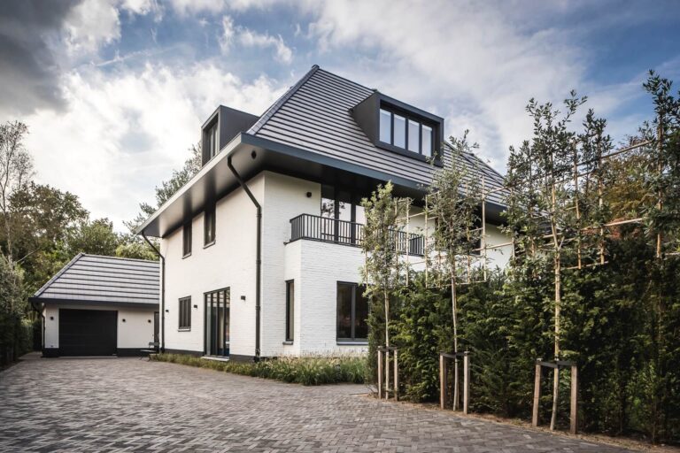 Luxe vrijstaande villa met witte gevel, donkere dakpannen, oprit en garage